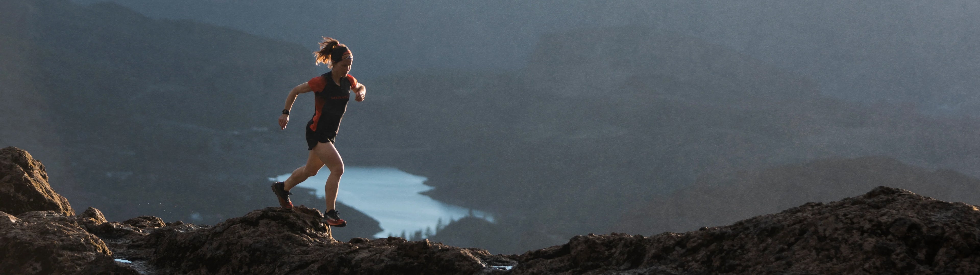 Person running on a rocky mountain with a scenic background