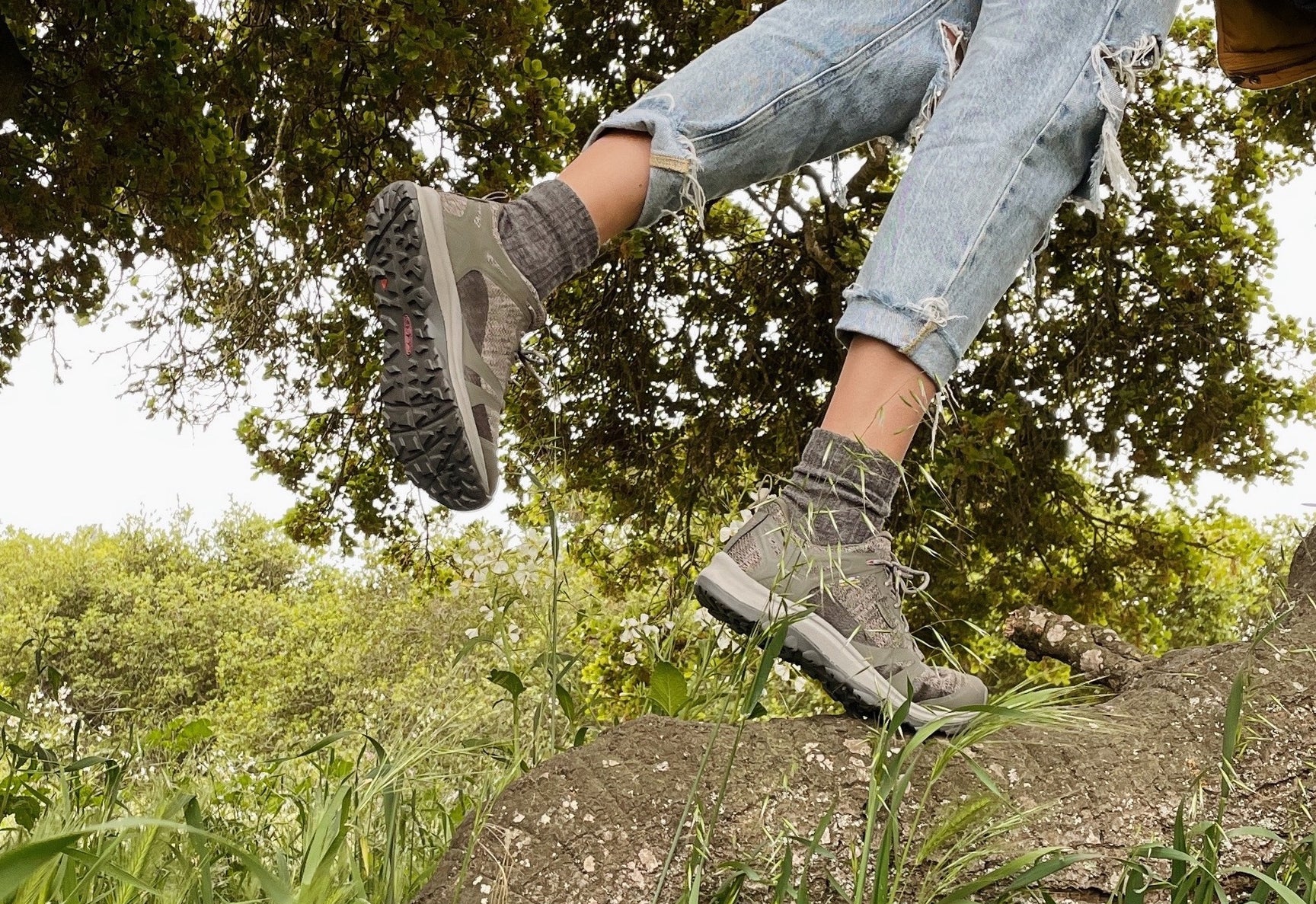 Person wearing hiking boots stepping over a log in a forest setting